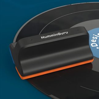 Black HumminGuru vinyl record cleaner with orange base, close-up on a vinyl record