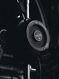 Nærbillede af den åbne hi-fi hovedtelefon Grado SR125x, set fra siden, der viser det sølvfarvede, cirkulære logo på den sorte ørekop