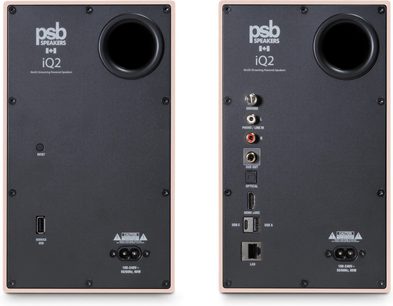 To PSB iQ2 connected-højttalere i beige sandstone, set bagfra med cirkulær basport og audio-, HDMI- og LAN-porte