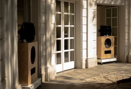 Staande hi-fi-luidspreker in licht houtafwerking met zwarte luidspreker en zwarte bovenmodule, driekwartaanzicht