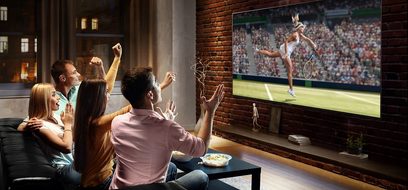 Panasonic TX-65JX940E-fladskærms-tv, der viser en kvindelig tennisspiller i aktion, set af en familie på 4 personer, der sidder på en sofa