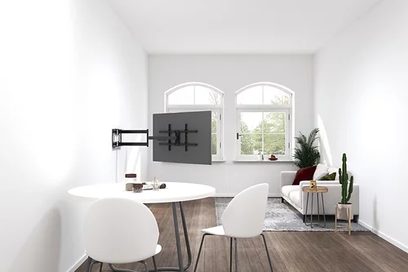Minimalistisk, moderne hvid stue med sofa, rund sofabord, vægmonteret tv, store vinduer og grønne planter