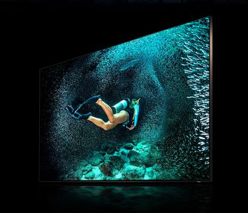 Samsung QE65Q900R-tv, der viser en undervandsdykker i turkisblåt vand med luftbobler