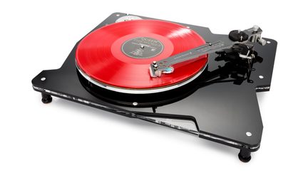 Platina de vinilo negra de acrílico brillante con plato que sostiene un disco de vinilo rojo translúcido, brazo de lectura metálico montado a la derecha, pies ajustables, vista en perspectiva ligeramente desde arriba