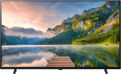 Televisore Panasonic TX-65JX800E che mostra un paesaggio montuoso con lago e foresta, cielo nuvoloso e riflessi nell'acqua
