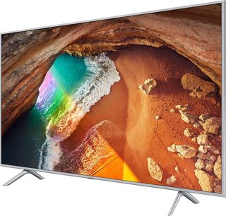 Samsung QE65Q64R-tv, der viser en strand med klipper, regnbuebølger og en tunnel i klippen