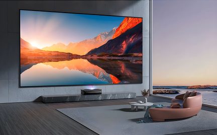 Black ultra-short-throw projector with giant wall-mounted home theater screen in a modern living room