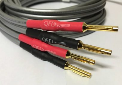 Audio kabely QED Reference XT40i, banánkové konektory pozlacené zlatem, červený a černý plášť, na šedém pozadí, detailní záběr