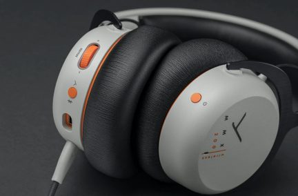 Grå og sort hovedtelefon, tykke puder, orange knapper, justeringshjul, tilsluttet kabel, nærbillede