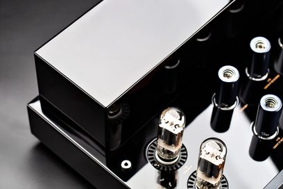 Cayin CS-6PH -hifi-tehovahvistin, kiiltävän musta metallirunko lähikuvassa ylhäältä päin, suorakulmainen kiiltävä muuntajakotelo ja kaksi lasista elektroniikkaputkea pyöreillä kannattimilla