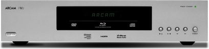 „Arcam FMJ BDP100" sidabrinės spalvos 4K „Blu-ray" grotuvas, priekinis vaizdas, ekrane rodoma „ARCAM", matomos mygtukai ir jungtys