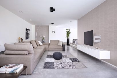 Moderne woonkamer met beige bank, grijze tapijt, witte en zwarte meubels. Muur van witte bakstenen, inbouwverlichting in het plafond
