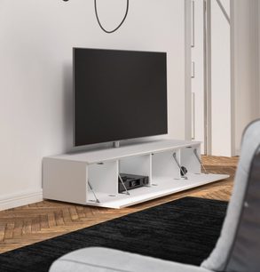 Bílý televizní nábytek s otevřenými policemi, černý držák na TV, zásuvky, na parketové podlaze s černobílým kobercem