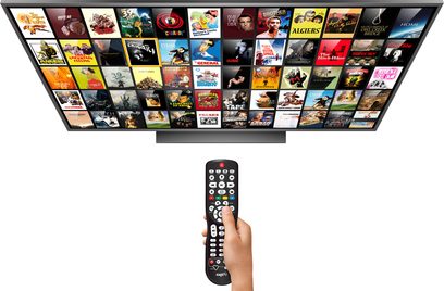Sort Zappiti-fjernbetjening med farveskærm, der viser ikoner, holdt i en hånd foran en stor tv-skærm, der viser miniaturebilleder af film og tv-serier