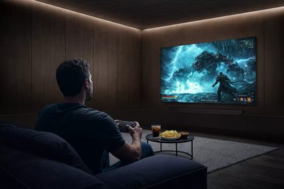 Samsung TQ77S92H 2026 fladskærms-tv til vægmontering, set i en mørk stue med et fantasy-videospil på skærmen