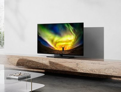 Panasonic TX-48LZ980E-fladskærm, der viser et grønt og gult nordlys, placeret på et lyst trækabinet