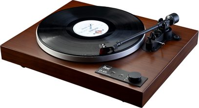 Hi-fi gramofon Dual CS 429 WN v orehovi izvedbi, pravokoten ohišje iz rjavega satiniranega lesa, pogled s sprednje strani pod rahlim kotom od zgoraj, srebrn okrogel pladenj z nameščeno črno vinilno ploščo, črna ročica in črna upravljalna plošča z vrtljivim gumbom