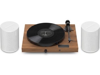 Vinylspelare i träfinish med svart skiva och två vita Sonos-högtalare, ovanifrån