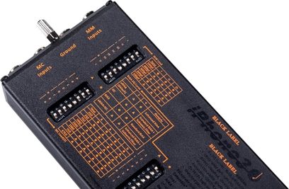 Phono-forforstærker iPhono3 micro Black Label, set fra en vinkel, sort overflade med orange inskriptioner, synlige kontakter og stik.
