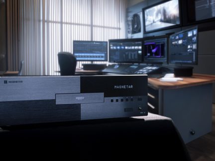 Lettore Blu-ray UHD Magnetar MK II nero metallizzato davanti a una postazione di montaggio video multi-schermo