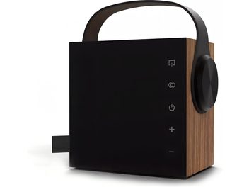Bærbar Bluetooth-højttaler Morel Biggie eg, set fra højre forhjørne, kubisk kabinet med sider i egetræsfiner og mat sort front, udstyret med sort buet bærehåndtag øverst, stor sort cirkulær drejeknap på højre side og lodret placerede berøringsikoner til betjening