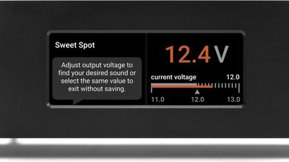 Display digitale che indica "12,4V tensione corrente" su un alimentatore nero con manopole di regolazione