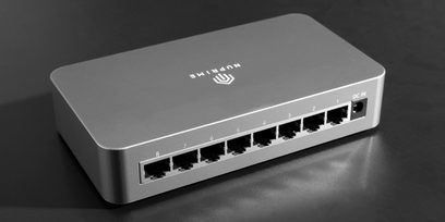 Stříbrný kovový switch a splitter Nuprime Omnia SW-8, pohled shora, 8 ethernetových portů, indikátor DC IN