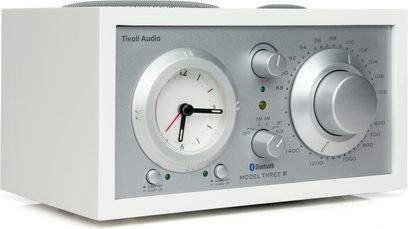 Tafelradio Tivoli Model Three BT in wit es, zilveren voorkant, klok links en grote instelknop rechts, 3/4-zijaanzicht