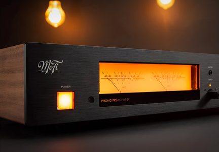 Preamplificador phono MoFi negro con laterales de madera y vúmetros retroiluminados en naranja, vista en tres cuartos