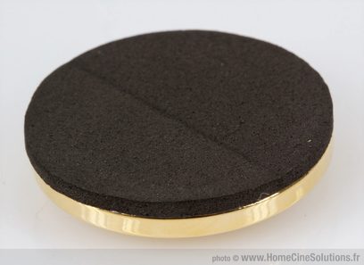 Disco preto em espuma densa, face superior plana, circundado por um anel dourado brilhante, visto de cima em fundo branco
