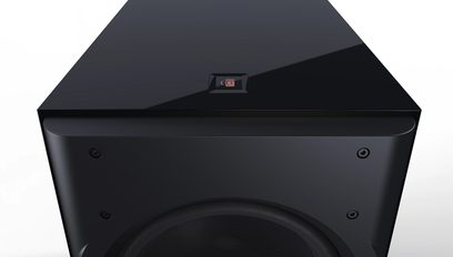 Subwoofer Perlisten D215s čierny lakovaný, pohľad z mierneho nadhľadu, hladký horný povrch s centrálnym logom, predná strana s čiastočne viditeľným kruhovým reproduktorom a viditeľnými skrutkami.
