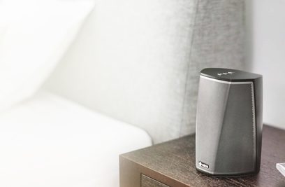 Trådløs tilsluttet Denon HEOS 1 HS2 højttaler i sort, set forfra, placeret på et træbord i et rum