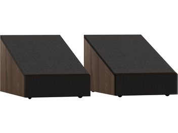 Pāris Dolby Atmos Monitor Audio Bronze AMS 7G skaldnes, trapecveida kārbas no riekstkoka ar priekšpusi un slīpi virsmu, klāti ar melnu audumu, trīs ceturtdaļu skats no priekšas