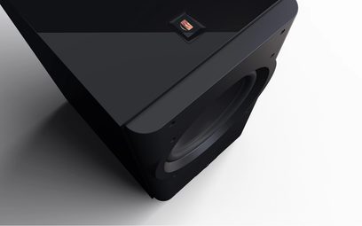 Subwoofer Perlisten D215s čierny lakovaný, pohľad zhora, horný roh s centrálnym logom, viditeľný kruhový reproduktor na prednej strane