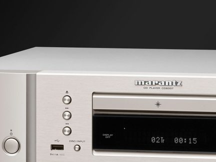 Fachada de leitor de CD Marantz em alumínio escovado prateado, close frontal, tela preta, botões redondos, porta USB, gaveta