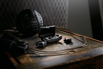 Sorte trådløse in-ear hovedtelefoner, sort kabel, på slidt træoverflade, tæt ovenfra-udsigt
