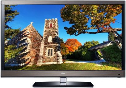 LG 47LW570S-fladskærm viser et stenbygningskirkebillede omgivet af træer med efterårsfarver, set forfra