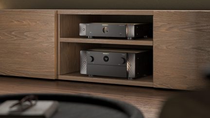 Svarte Marantz hjemmekinoforsterkere stablet i et TV-møbel i lyst tre, med front i børstet aluminium
