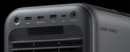 Mat anthracite gray alloy case, three-quarter rear view showing DC ports, two HDMI, USB-A, USB-C, 3.5 mm audio/optical jack, perforated ventilation grille, and side “LASER FORGE” logo
