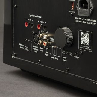 Schwarze Rückwand mit RCA- und XLR-Anschlüssen, Lautsprecher-Eingangsklemmen, gerändeltem Knopf, QR-Code, ARC-Port und Stromanschluss.