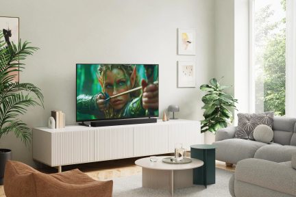 Sort fladskærms-tv på hvidt tv-møbel i en lys moderne stue med soundbar