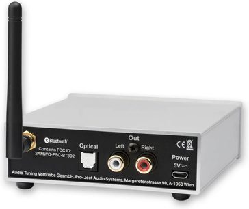 Pro-Ject BT Box S2 HD wireless transmitter in silver, rear view, rectangular casing, black vertical antenna on the left, red and white RCA connectors, optical port, USB-C power port, circular black feet.