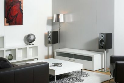 Sorte søjlehøjttalere, hvidt sofabord, sort sofa, globus, rødt abstrakt maleri, forkromede lamper