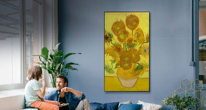 Oliemaleri af gule solsikker i en vase på gul baggrund, hængende på væggen i en moderne stue med blå sofa