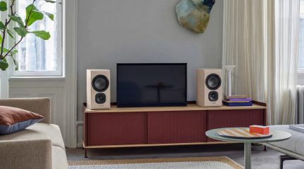 Valgete riiulikõlarite paar mõlemal pool telerit bordoopunast soonilise madala kapi peal modernses elutoas