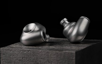 Hi-Fi In-Ear-Kopfhörer aus mattem grauem Metall, ergonomische Gehäuse auf schwarzer, texturierter Halterung platziert