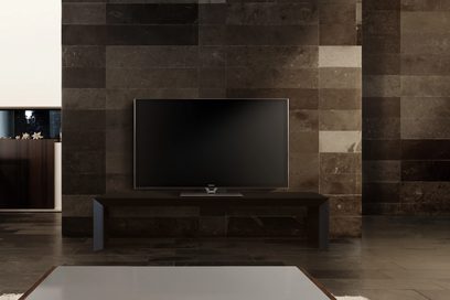 Panasonic TX-P65VT60E 65 tommer fladskærms-TV slukket, set forfra, stående på mørkt træmøbel foran stenmur
