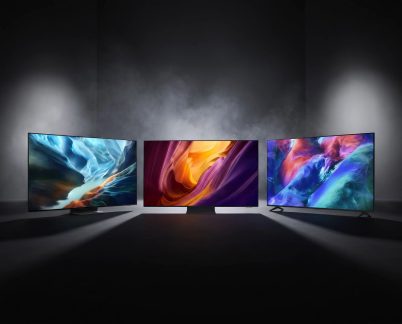 Three flat-screen televisions displaying colorful abstract visuals in a dark room