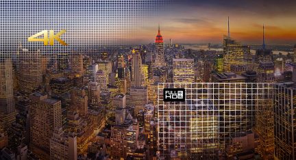Vista aerea notturna di una città densamente popolata con numerosi grattacieli illuminati, tra cui l'Empire State Building al centro