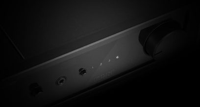 Lähikuva Rega io -stereovahvistimen mustasta etupaneelista, jossa on 3 pyörivää nuppia ja keinukytkin